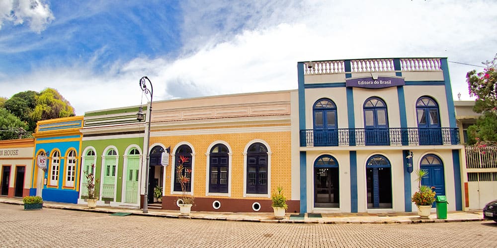 Une série de maisons de style colonial aux façades peintes en bleu, vert et jaune