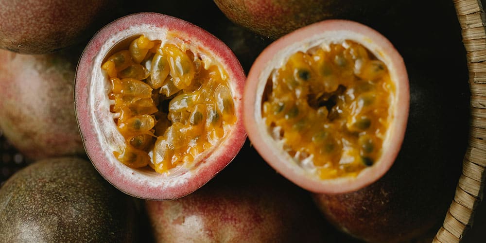 Gros plan sur des fruits de la passion coupés en deux, révélant leur pulpe jaune brillante et juteuse.