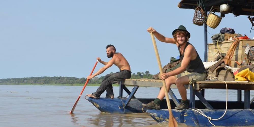 Deux hommes rament avec des pagaies en bois depuis leur radeau bleu