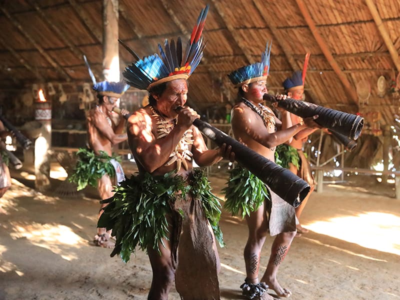 Membres d’un peuple autochtone d’Amazonie jouant de la musique traditionnelle dans une hutte en bois