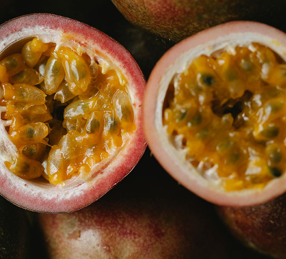 Gros plan sur des fruits de la passion coupés en deux, révélant leur pulpe jaune brillante et juteuse.