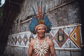 Portrait d’un membre d’une communauté indigène amazonienne portant une coiffe colorée et des ornements traditionnels